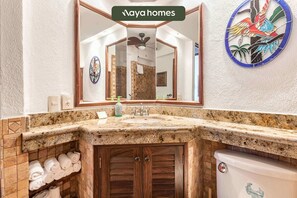 A bathroom with a granite countertop, a wooden vanity, a toilet, and a mirror with a reflection of the room.