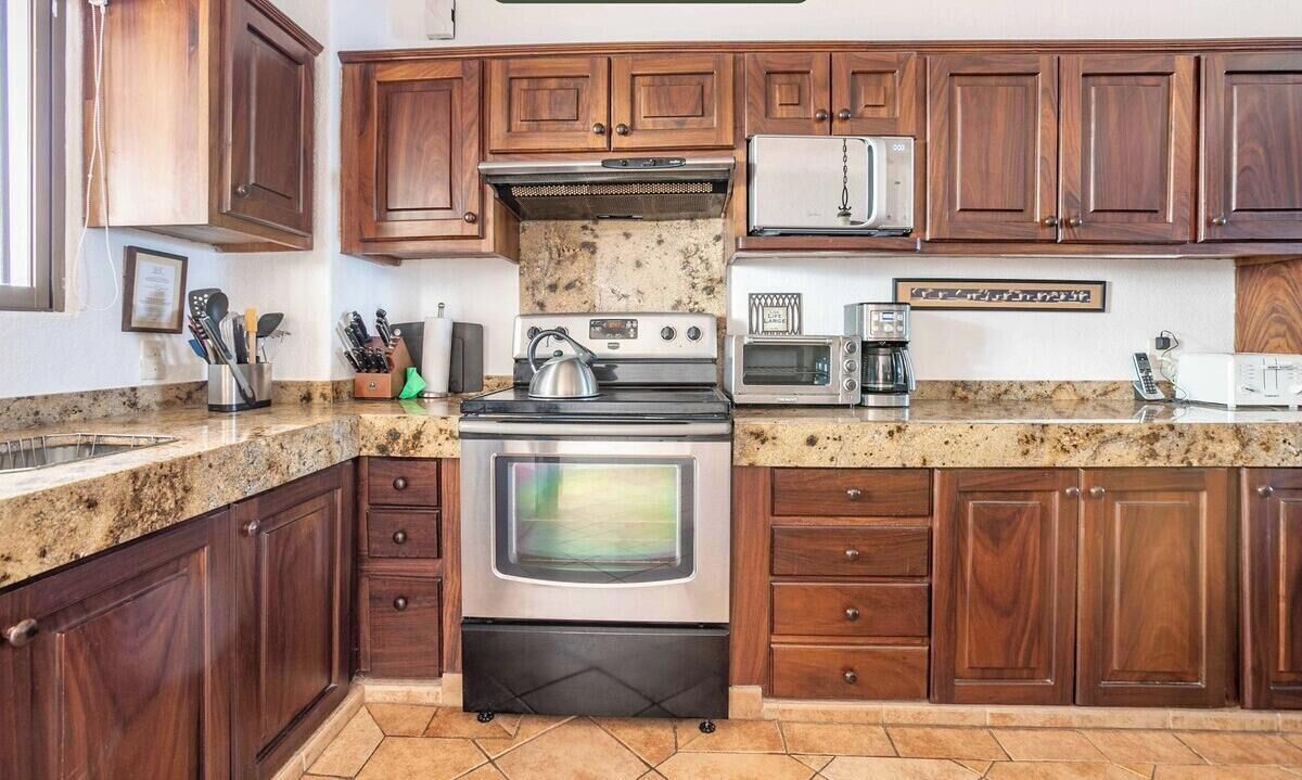 A kitchen with wooden cabinets, a stainless steel stove, a microwave, and a toaster.