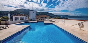 Une piscine sur le toit offrant une vue dégagée sur les montagnes et, au loin, sur le paysage urbain.