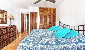 A bedroom with a bed, wooden wardrobe, and a dresser.