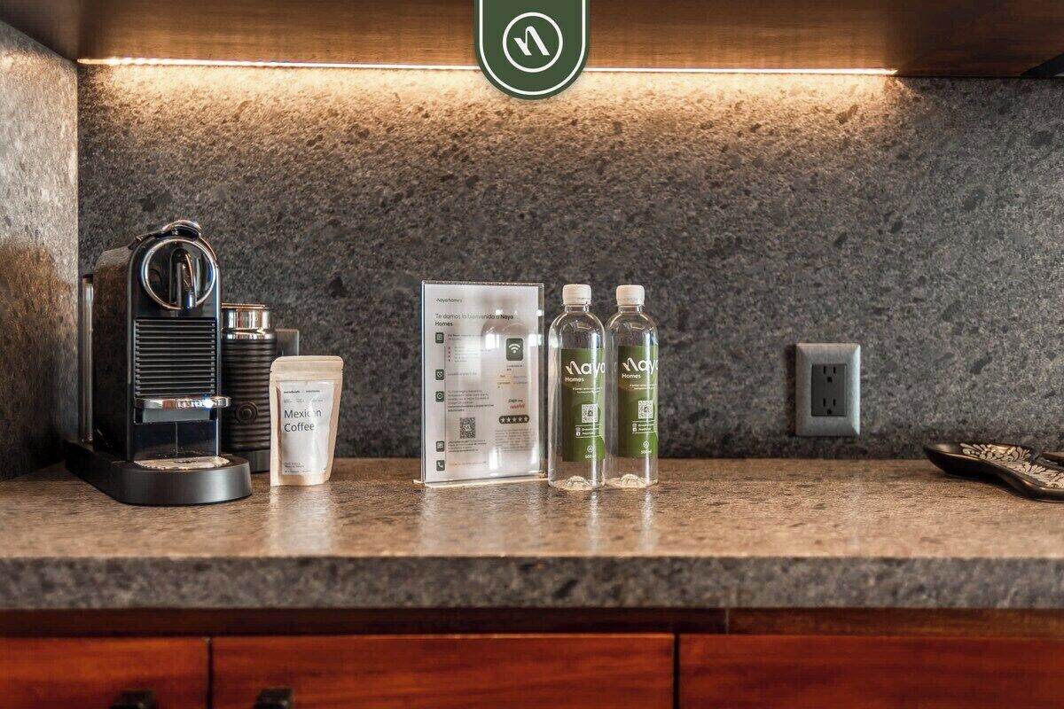 A coffee machine, a coffee pod, two bottles of water, and a sign on a countertop.