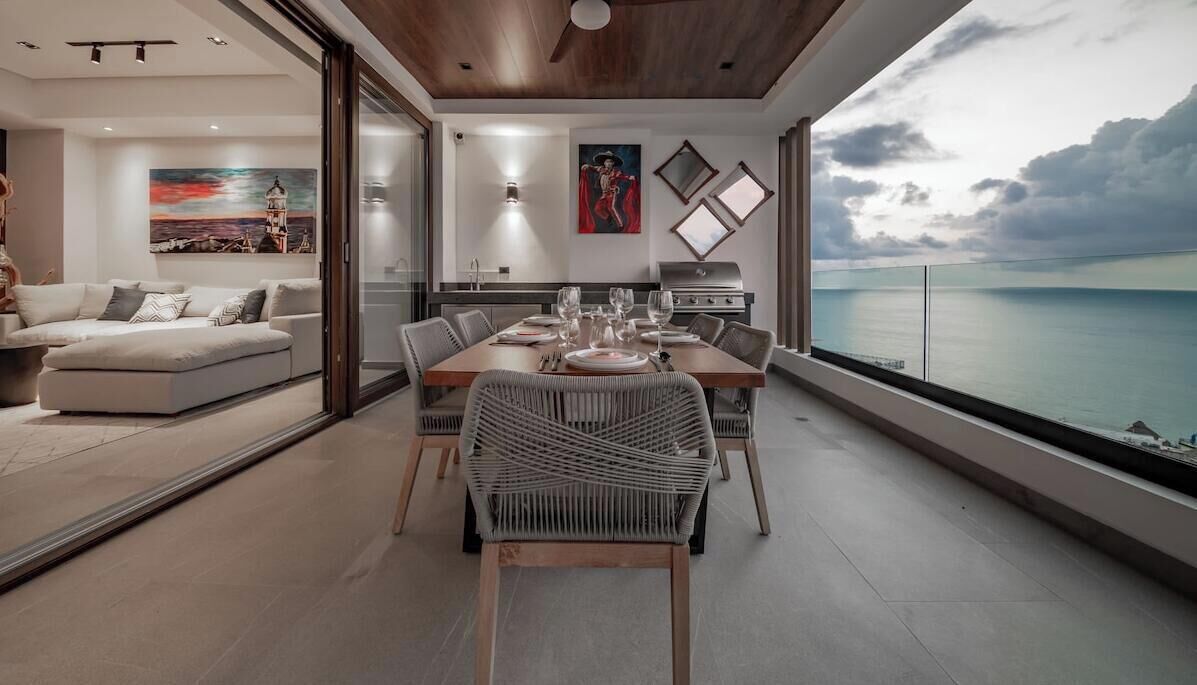 A modern dining area with a view of the sea, a sofa, and artwork on the walls.