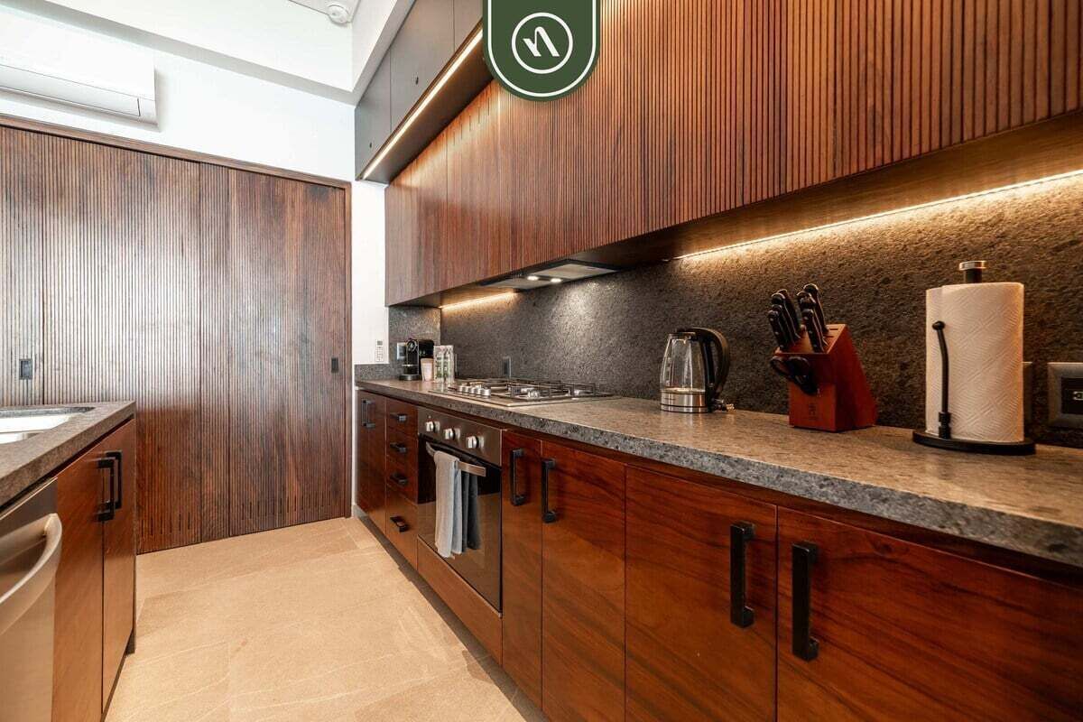 Une cuisine moderne avec des meubles en bois, un plan de travail en granit et des appareils électroménagers en acier inoxydable.