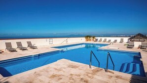 A rooftop pool with a clear view of the ocean, lounge chairs, and a covered seating area. - Ocean View 2Br Condo-balcony-beach-pool 710 (Puerto Vallarta)