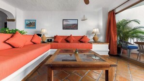 A living room with a sofa, two side tables with lamps, a coffee table, and a view of the outdoors. - Ocean View 2Br Condo-balcony-beach-pool 710 (Puerto Vallarta)