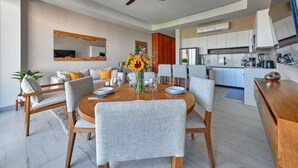 A modern dining area with a round table, grey upholstered chairs, and a ceiling fan. - Amazing 2BR Apt -private Balcony - Rooftop Pool (Puerto Vallarta)