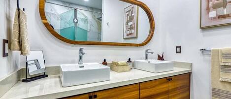 Un baño con dos lavamanos, un mueble de tocador de madera, un espejo y un perchero para toallas.