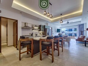A modern kitchen with a central island, bar stools, and a dining area with a sofa and chairs. - Amazing 2 BR Condo in Versalles - Rooftop Pool (Puerto Vallarta)