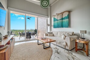 Ein modernes Wohnzimmer mit einer Couch, einem Couchtisch und Blick durch eine Glastür.