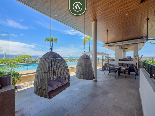 A rooftop terrace with hanging chairs, a pool, and a dining area.
