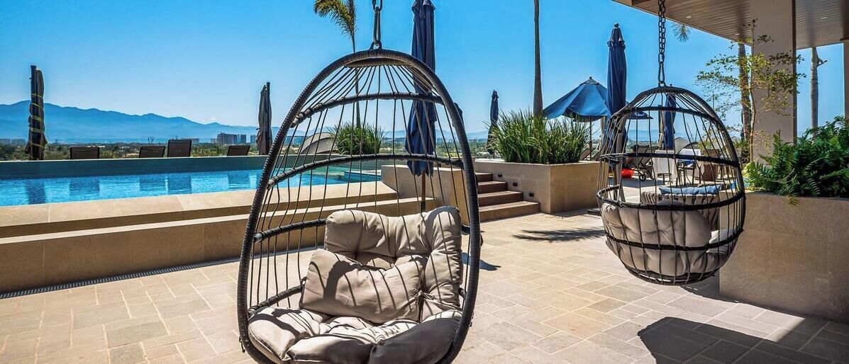 A poolside area with hanging chairs and a view of the mountains.
