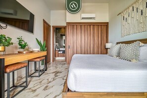 Une chambre à coucher comprenant un lit, un bureau avec des chaises, un téléviseur et un appareil de climatisation.