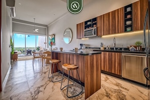 A modern kitchen with wooden cabinets, a marble countertop, and bar stools.