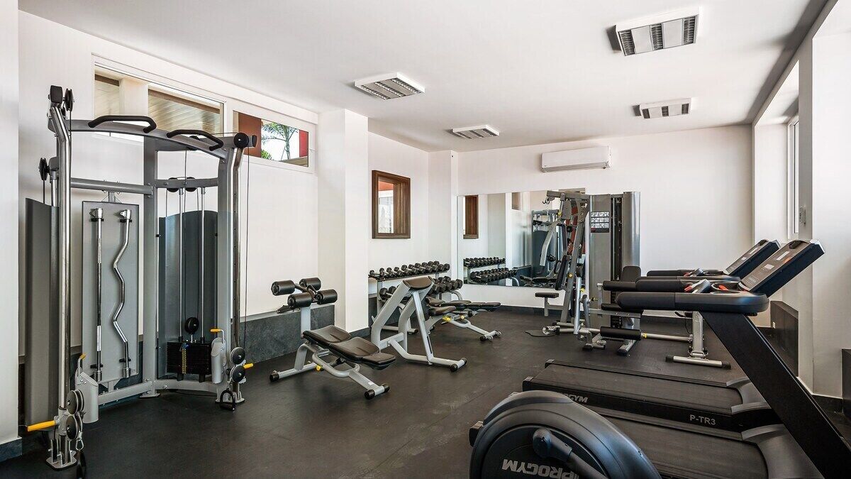 Een fitnessruimte met loopbanden, krachttrainingsapparaten en gewichten.