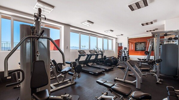 Un gimnasio con cintas de correr, máquinas de pesas y bancos.