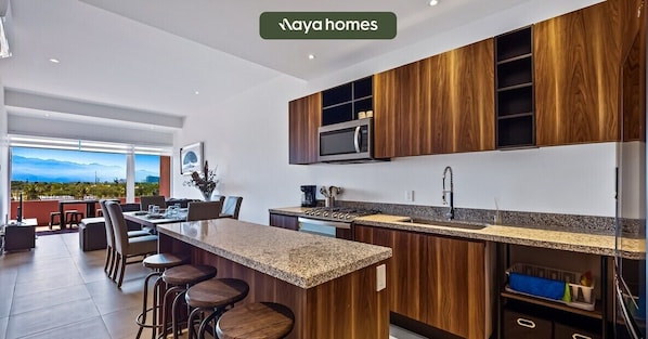 A modern kitchen with wooden cabinets, a granite countertop, and a large island with bar stools.