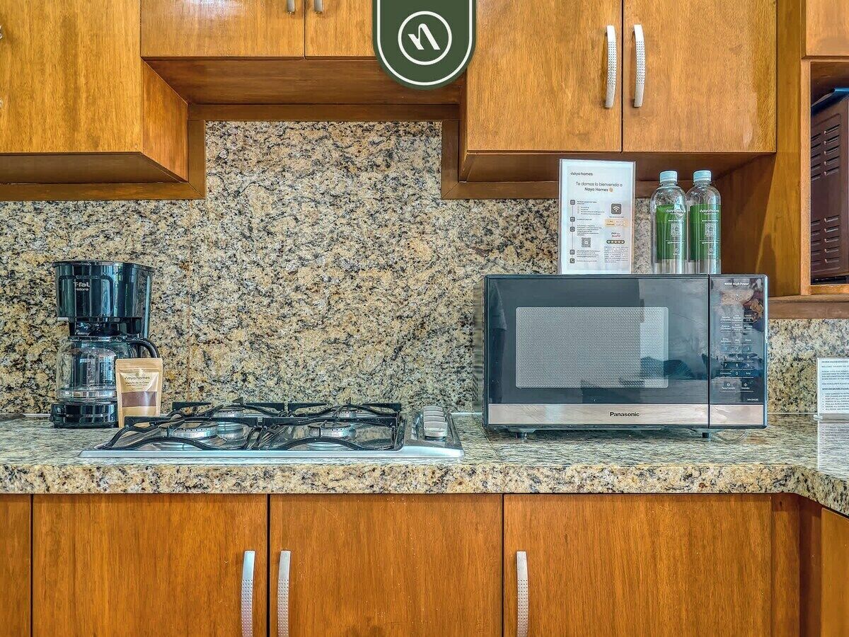Eine Küche mit Granit Arbeitsplatten, einem Gasherd, einer Kaffeemaschine, einer Mikrowelle und Holzschränken.