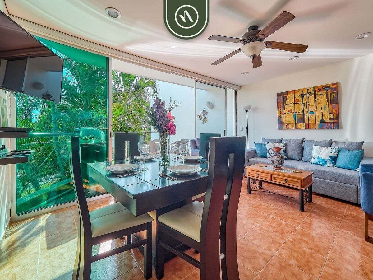 A dining area with a glass table, chairs, and a view of greenery outside.