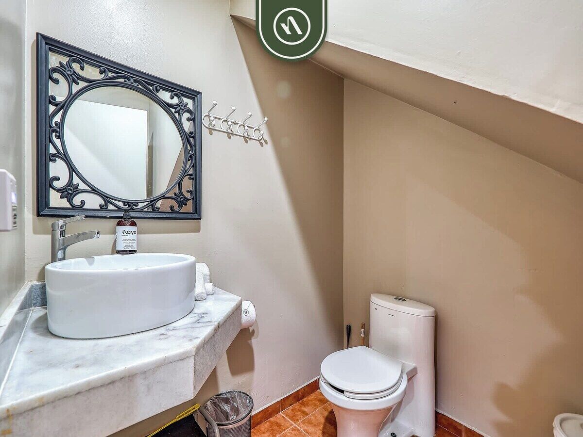 A bathroom with a white sink, a mirror with ornate frame, a toilet, and a towel rack.