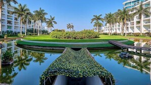 Un hôtel doté d’une piscine, de palmiers et d’une pelouse bien entretenue.