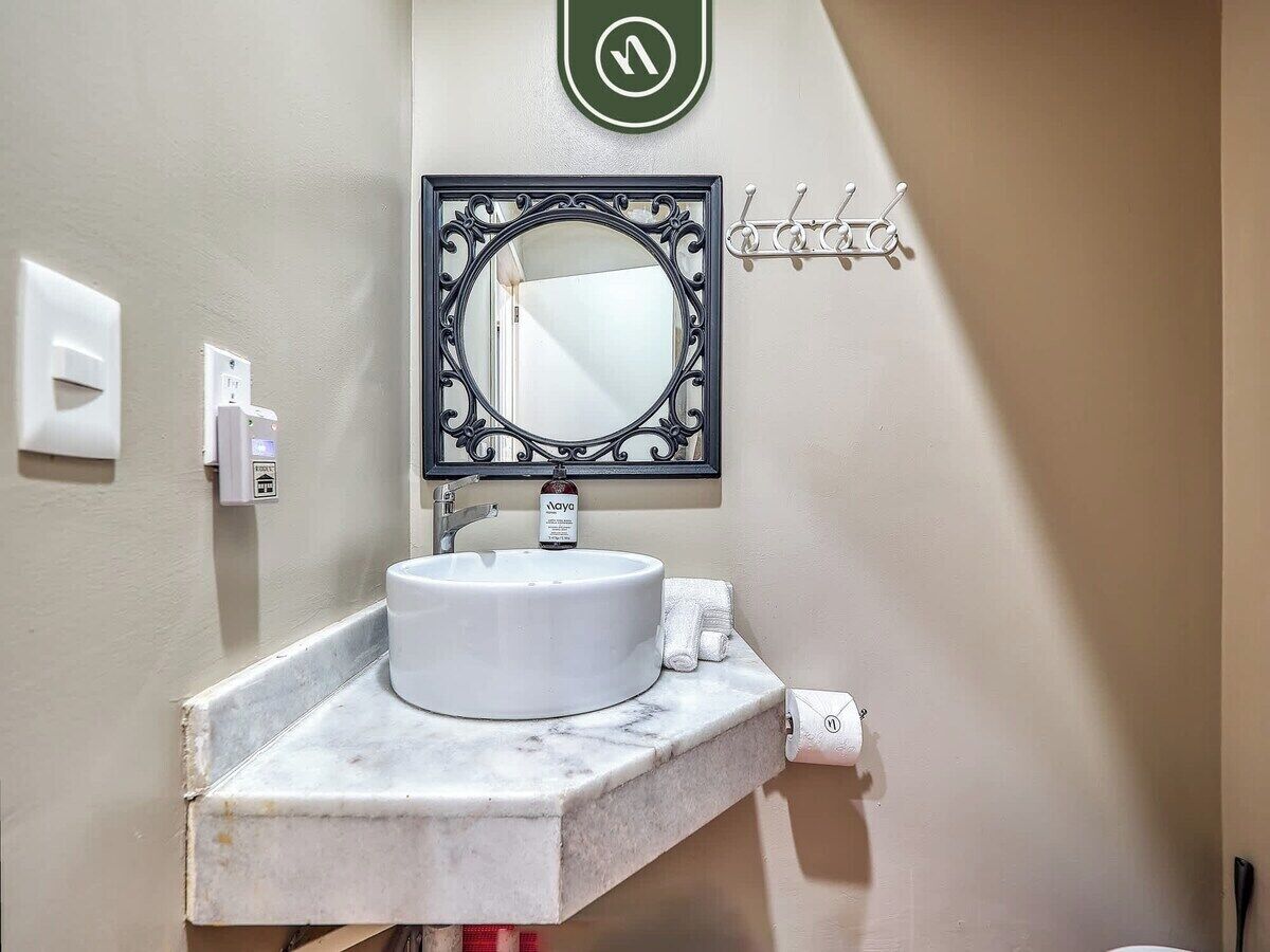A bathroom with a white sink, a mirror with an ornate frame, a towel rack, and a hand dryer.
