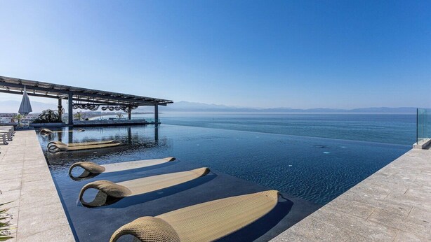 An infinity pool with lounge chairs, a pergola, and a view of the sea. - Udara Udara 2K (Bucerías)