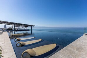 An infinity pool with lounge chairs, a pergola, and a view of the sea. - Udara Udara 2K (Bucerías)