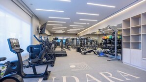 A gym with cardio machines, weightlifting equipment, and a wall-mounted TV. - Udara Udara 2K (Bucerías)