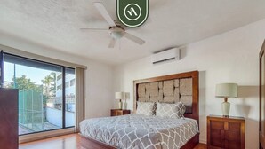 A bedroom with a large bed, a ceiling fan, an air conditioning unit, and a view through a sliding door. - 2 BR Condo in Hotel - Beach - Pools - Kids Club (Puerto Vallarta)
