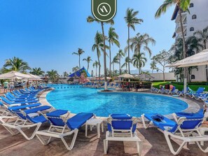 A pool area with lounge chairs and palm trees. - 2 BR Condo in Hotel - Beach - Pools - Kids Club (Puerto Vallarta)