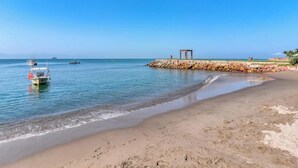 A beach with a rocky breakwater, calm water, and a small boat. - 2 BR Condo in Hotel - Beach - Pools - Kids Club (Puerto Vallarta)