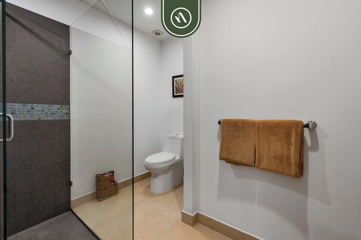 Une salle de bain avec une porte de douche en verre, des toilettes et un porte-serviettes avec une serviette.