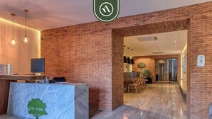 A reception area with a marble counter, a brick wall, and a hallway leading to a dining area. - Elegant 2 BR Condo With Amazing Rooftop Pool (Puerto Vallarta)