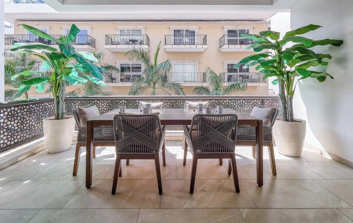 Ein Balkon mit Esstisch, Stühlen und Topfpflanzen.