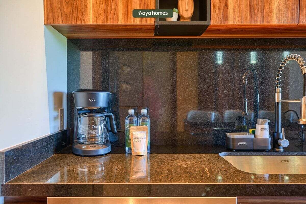 Una cocina equipada con cafetera, dispensador de agua y lavamanos.