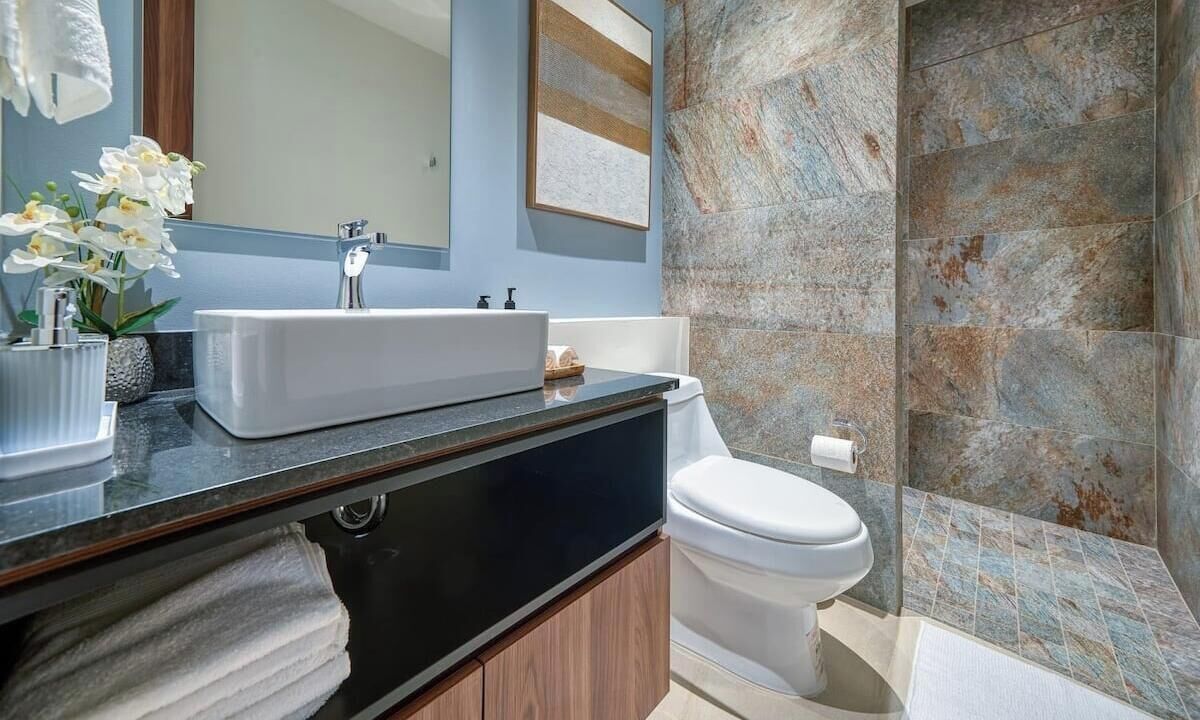 A modern bathroom with a large sink, toilet, and shower area.