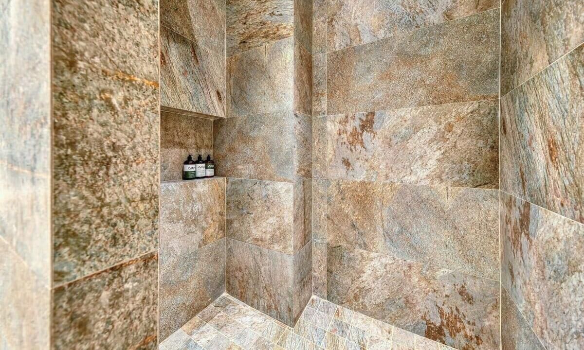Ein Badezimmer mit großen Steinfliesen und einem Ablagefach für Toilettenartikel.