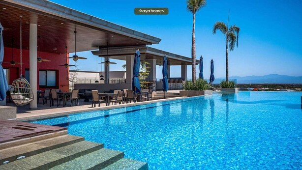 A poolside area with a covered seating area, palm trees, and a view of the mountains. - Luxury 2BR Condo in Nuevo Vallarta - Rooftop Pool (Nuevo Nayarit)