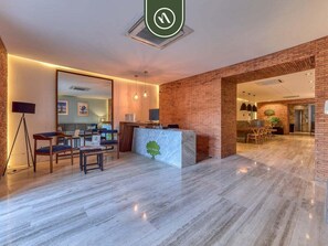 A modern hotel lobby with a reception desk, seating area, and a visible kitchen in the background. - Luxury 2 BR in Romantic Zone - Rooftop Pool (Puerto Vallarta)