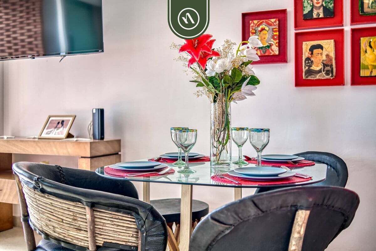Un espace repas avec une table ronde en verre, dressée pour quatre personnes, entourée de chaises noires.