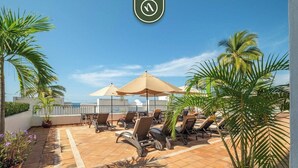 A rooftop terrace with lounge chairs, umbrellas, and potted plants. - Amazing 1 BR Condo - Terrace - Pool - Romantic Zone (Puerto Vallarta)