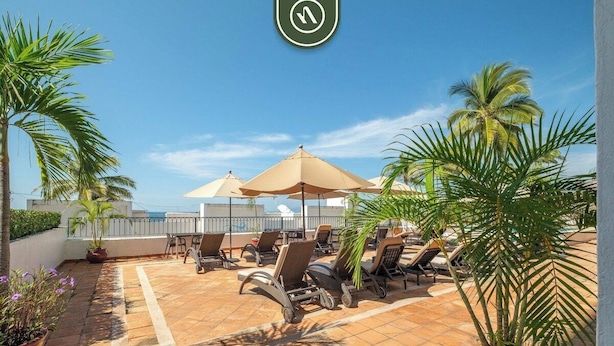 A rooftop terrace with lounge chairs, umbrellas, and potted plants. - Amazing 1 BR Condo - Terrace - Pool - Romantic Zone (Puerto Vallarta)