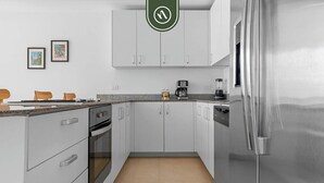 A modern kitchen with white cabinets, stainless steel appliances, and a granite countertop. - Beautiful 2 BR Condo Amazing Rooftop Pool - Gym (Puerto Vallarta)