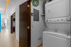 A modern kitchen with a white Frigidaire refrigerator and stove, a door with a green circular sign, and a hallway leading to a room with a blue accent wall.