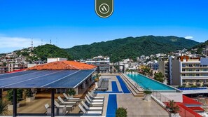 A hotel with a rooftop pool, a mountain backdrop, and a solar panel installation.