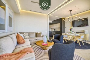 A modern living room with a sofa, coffee table, and dining area.