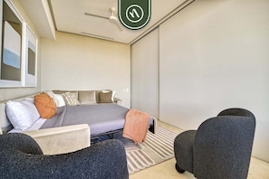 Une chambre moderne avec un lit, un bureau et deux chaises.