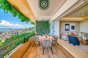 A balcony with a dining table, chairs, and a view of the cityscape.