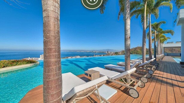 A wooden deck with lounge chairs and a pool overlooking a coastal view. - Luxury 1BR Condo With Private Terrace - Ocean View (Puerto Vallarta)
