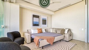 A bedroom with a bed, two wall-mounted pictures, a ceiling fan, and a large window. - Luxury 1BR Condo With Private Terrace - Ocean View (Puerto Vallarta)